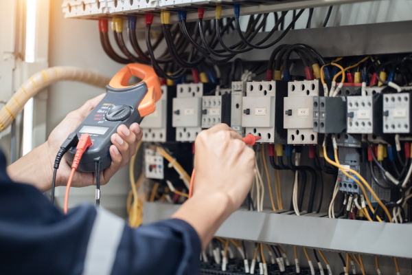 Electrician testing a commercial electrical panel with a clamp meter