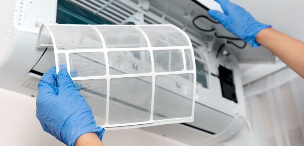 Technician cleaning an air conditioning filter during routine maintenance
