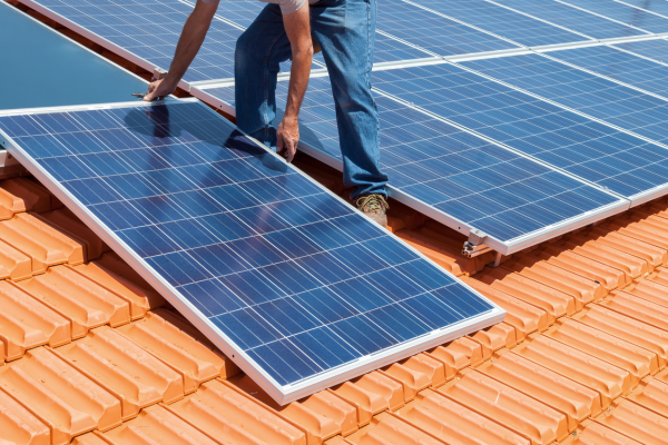 Electrician installing solar panels on a residential rooftop